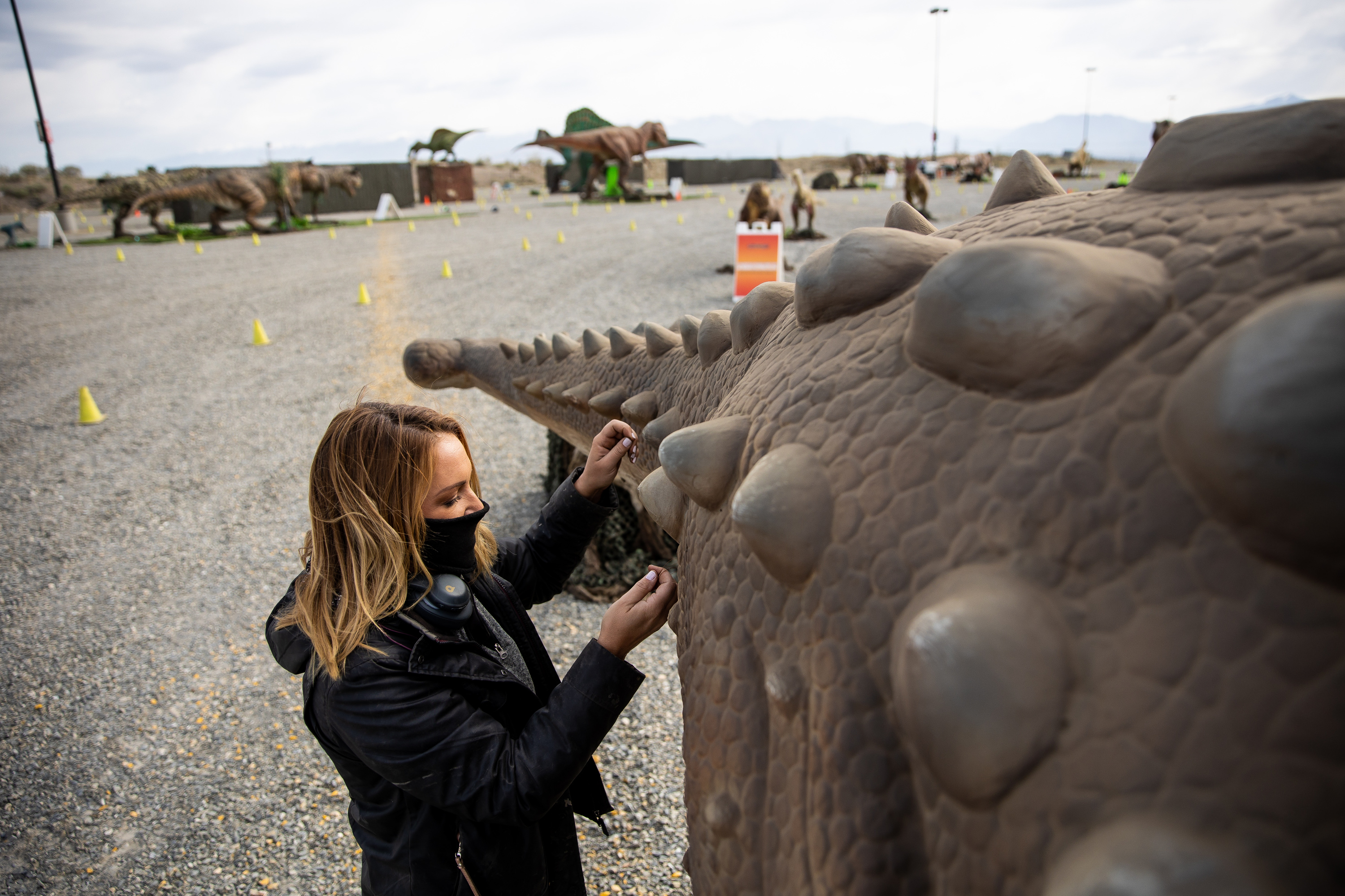 Cassandra Rose sews up a small "battle wound" suffered during transit on one of the dinosaurs on display ahead of the opening of "Jurassic Quest Drive Thru" at the USANA Amphitheatre in West Valley City on Friday, April 23, 2021.