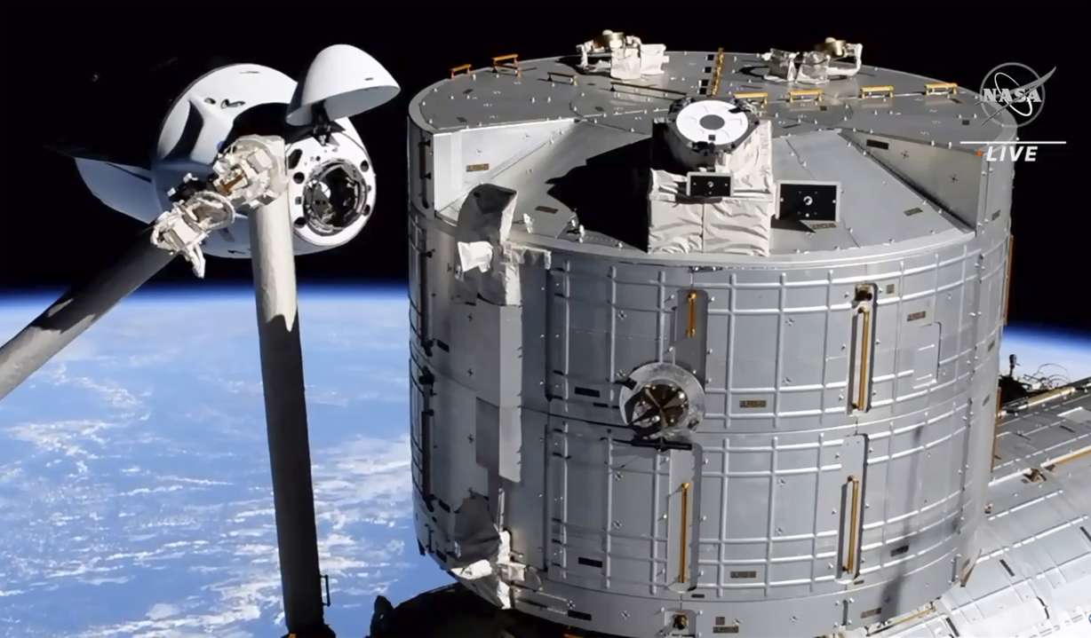 In this image made from NASA TV, the SpaceX Crew Dragon spacecraft, left, approaches to the international space station, Saturday, April 24, 2021. The recycled SpaceX capsule carrying four astronauts arrived at the International Space Station on Saturday, the third high-flying taxi ride in less than a year for Elon Musk's company.