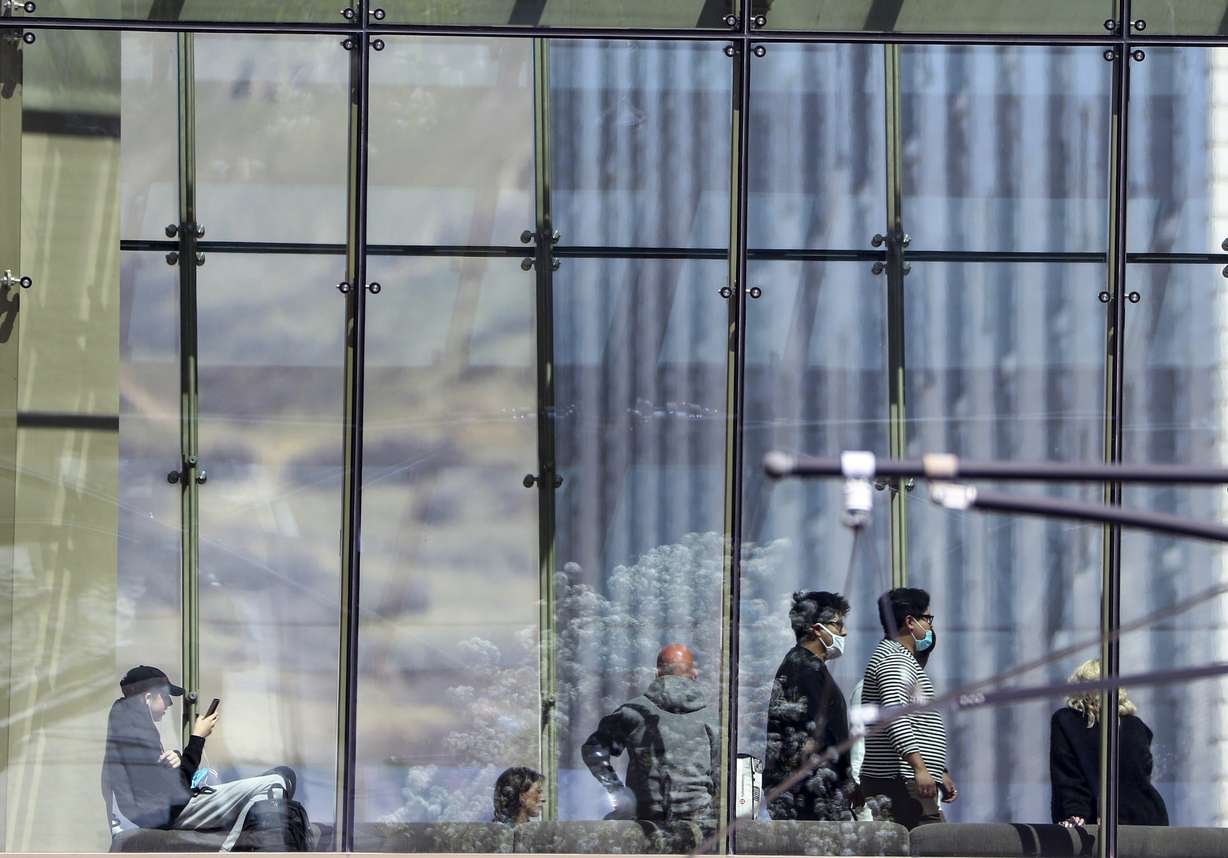 People wear masks as they cross the pedestrian skybridge at the City Creek Center downtown Salt Lake City on Friday, April 9, 2021.
