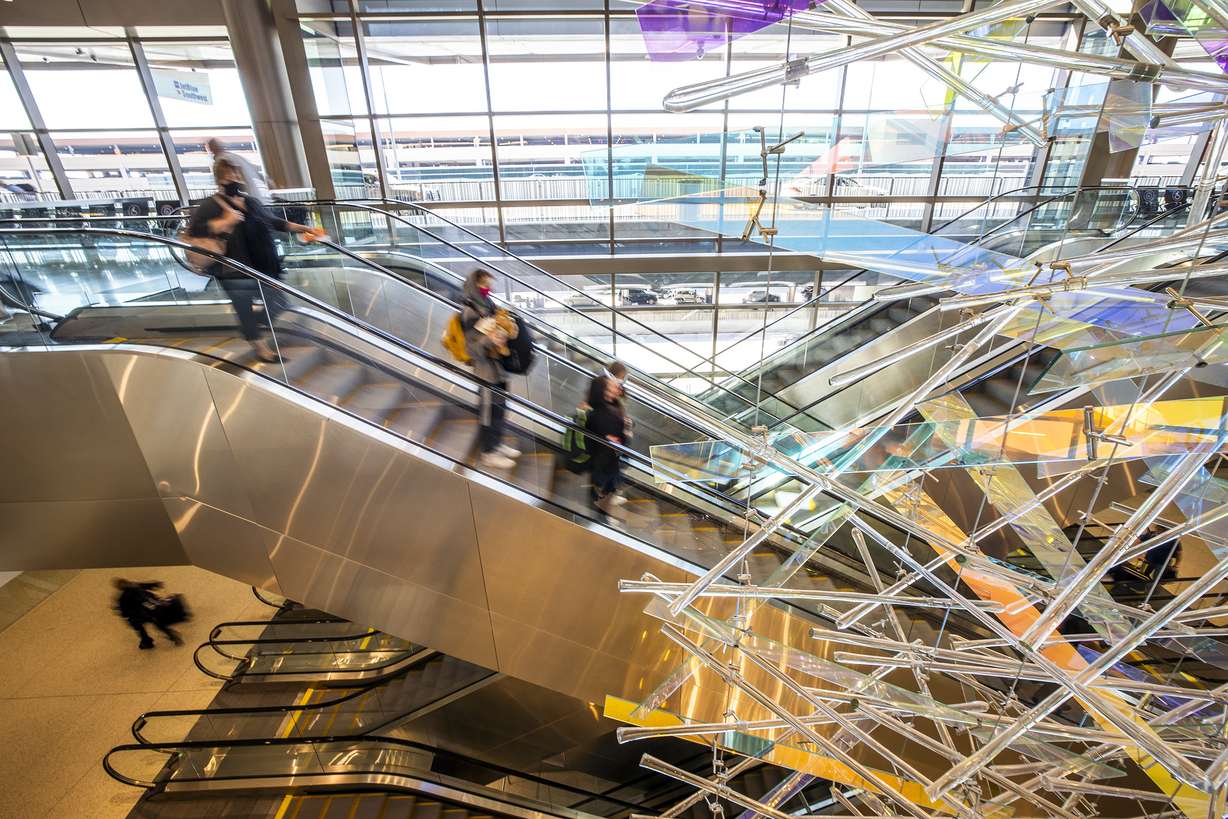 Travelers ride the escalators at the Salt Lake City International Airport on Friday, April 2, 2021.