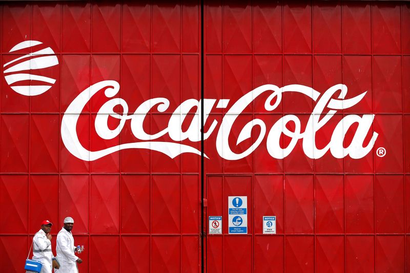FILE PHOTO: Workers walk past a Coca Cola logo painted on a gate at a Coca Cola factory in Nairobi, Kenya, June 7, 2018. REUTERS/Baz Ratner