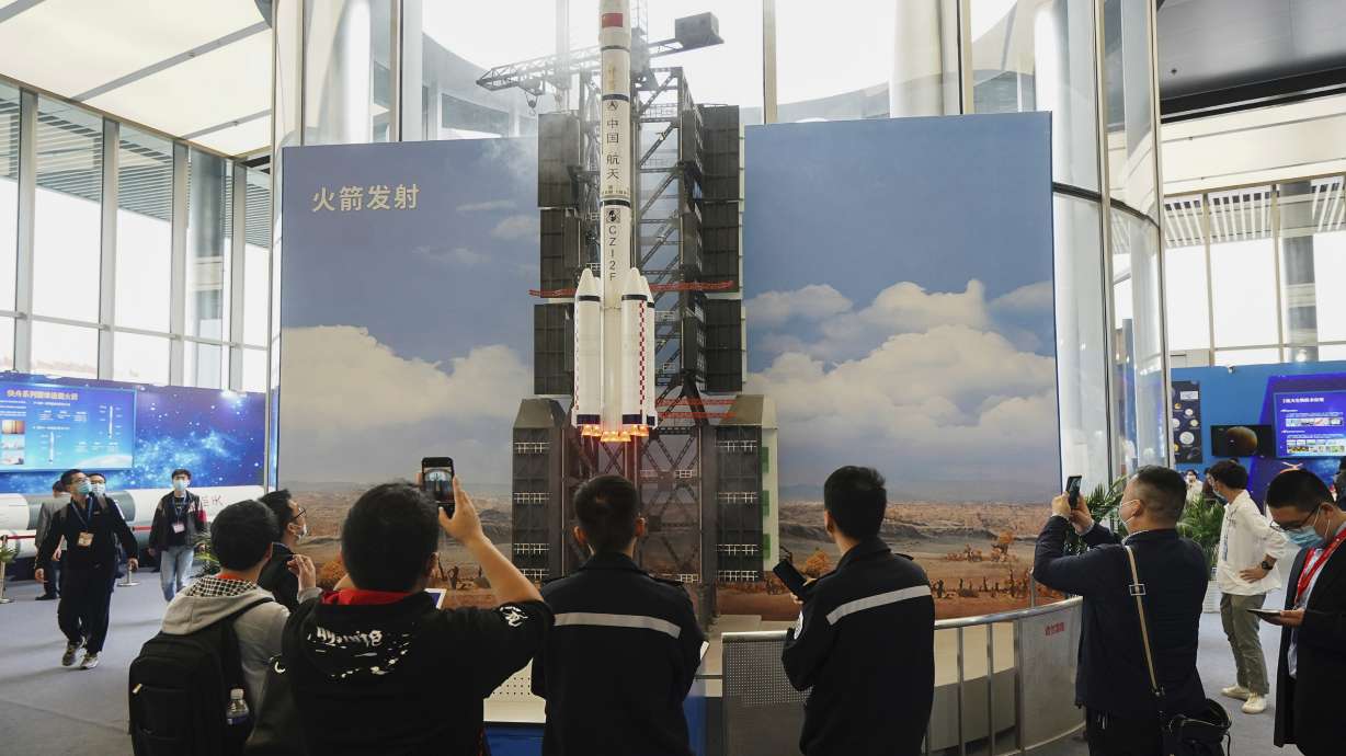 In this photo released by Xinhua News Agency, visitors view a simulated rocket launch on display at an exhibition featuring space science and achievement during the China Space Conference in Nanjing in east China's Jiangsu province on Saturday, April 24, 2021. Chinese researchers want to send more than 20 of China's largest rockets to practice turning away a sizable asteroid.