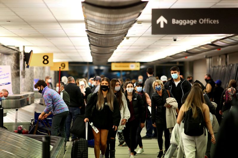 FILE PHOTO: Travelers wearing protective face masks to prevent the spread of the coronavirus disease (COVID-19) reclaim their luggage at the airport in Denver, Colorado, U.S., November 24, 2020. REUTERS/Kevin Mohatt