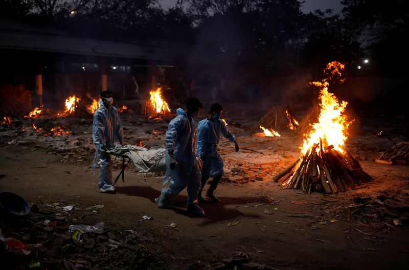 People carry a body of a man, who died from the coronavirus disease (COVID-19), during his cremation at a crematorium in New Delhi, India May 3, 2021. REUTERS/Adnan Abidi