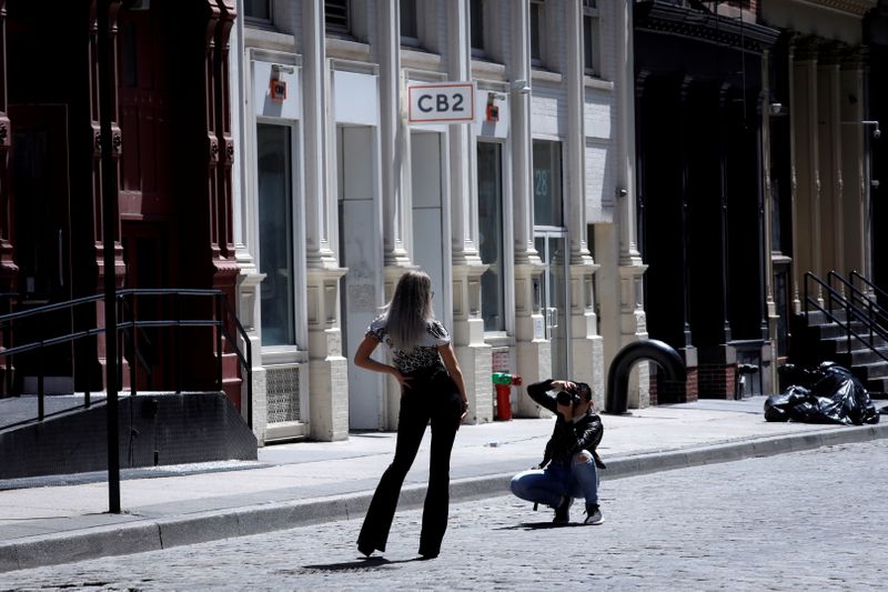 FILE PHOTO: A model poses for a photographer on an empty street in front of closed shops in Soho in Manhattan during the outbreak of the coronavirus disease (COVID-19) in New York City, New York, U.S., May 26, 2020. REUTERS/Mike Segar