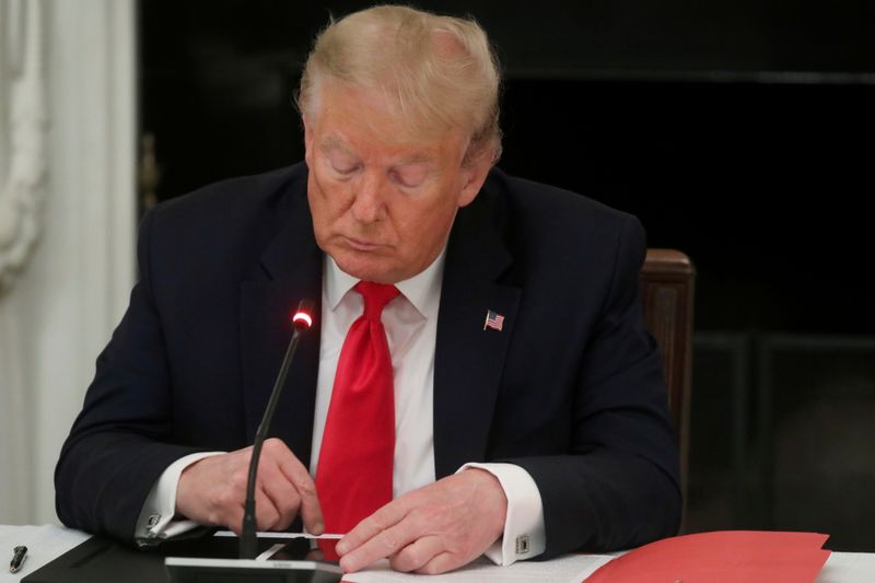 FILE PHOTO: U.S. President Donald Trump is seen tapping the screen on a mobile phone during a roundtable discussion on the reopening of small businesses in the State Dining Room at the White House in Washington, U.S., June 18, 2020. 