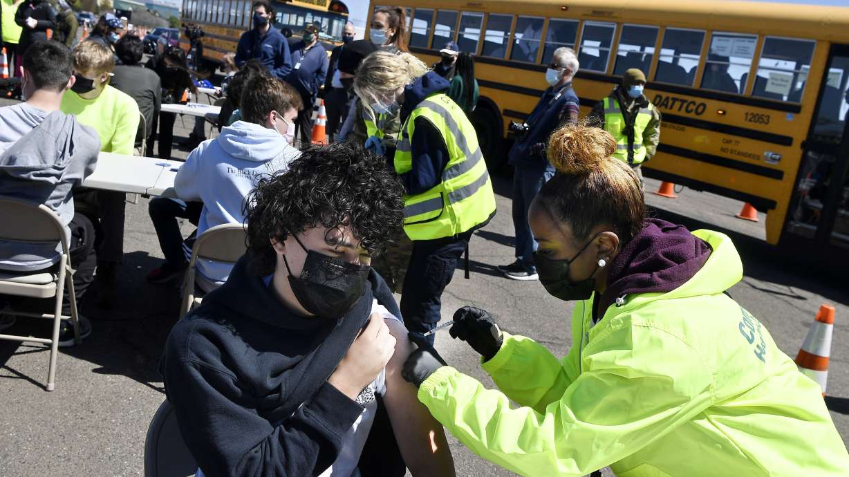 FILE - In this April 26, 2021, file photo, CREC Academy of Aerospace and Engineering sophomore Brian Acevedo, 16, receives a COVID-19 vaccine from nurse Myra Glass, of East Hartford, during a mass vaccination site at Pratt & Whitney Runway in East Hartford, Conn. Teams of experts are projecting COVID-19's toll on the U.S. will fall sharply by the end of July, according to research released by the government Wednesday, May 5.