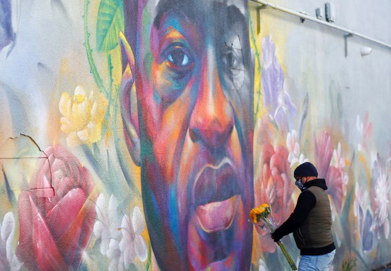 FILE PHOTO: A man places flowers at a mural of George Floyd after the verdict in the trial of former Minneapolis police officer Derek Chauvin, found guilty of the death of Floyd, in Denver, Colorado, U.S., April 20, 2021. REUTERS/Kevin Mohatt