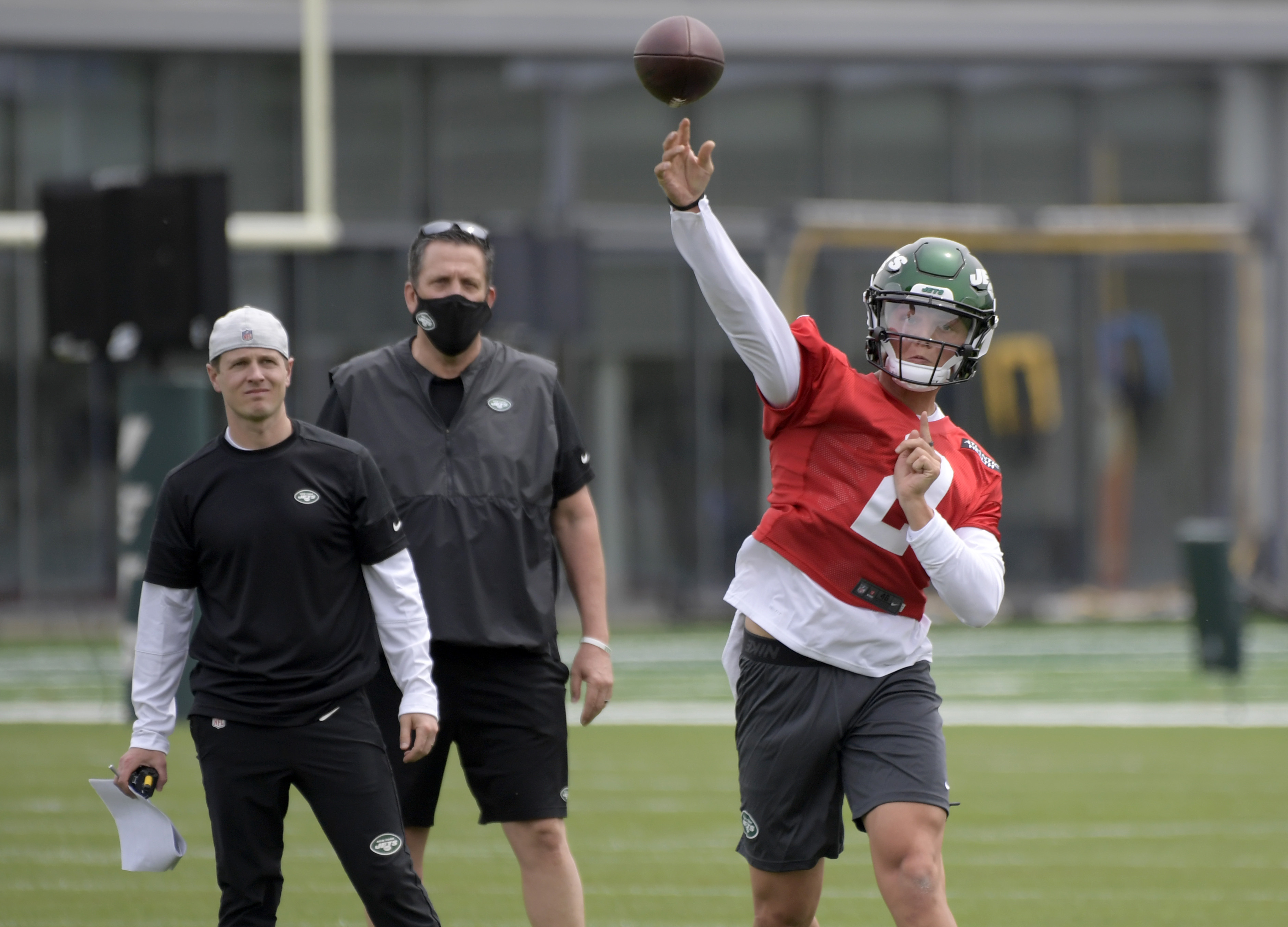 New York Jets first-round draft pick Zach Wilson (2) works out as offensive coordinator Mike Lafleur, left, and passing game specialist Greg Knapp, center, look on during NFL football rookie camp, Friday, May 7, 2021, in Florham Park, N.J.