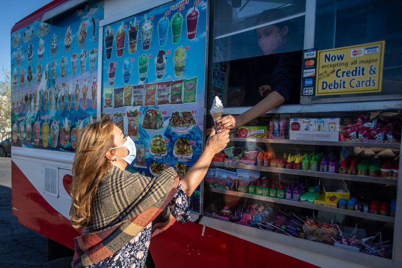 Health care worker Liliana Arferis, left, receives
donated ice cream from Vanessa Camargo, right, from the Camargo Ice
Cream truck at a COVID-19 vaccine pop-up event at Reams in Magna on
Monday, May 3, 2021. The Salt Lake County Health Department is
doing vaccination pop-up events with its mobile health
center.