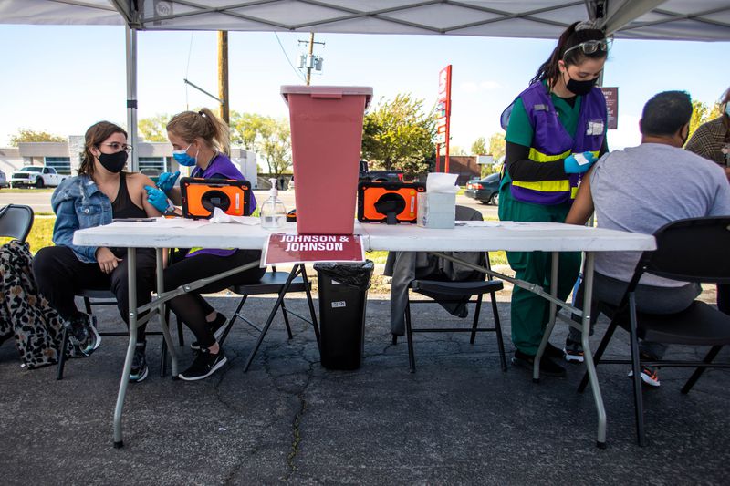 Estefania Matos, left, receives a COVID-19 vaccine from
health care worker Danielle Davis as health care worker Nadia
Swanson gives Danny Revete a COVID-19 vaccine at a pop-up
vaccination event at Reams in Magna on Monday, May 3, 2021. The
Salt Lake County Health Department is doing vaccination pop-up
event with its mobile health center.