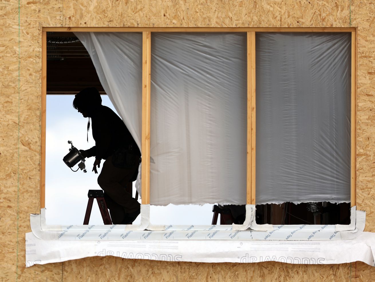 A worker installs a recessed light fixture at a
building site in South Jordan on Monday, May 10, 2021.
Unprecedented increases in the cost of lumber and other building
supplies is driving up prices in Utah’s already red-hot real estate
and renovation markets.