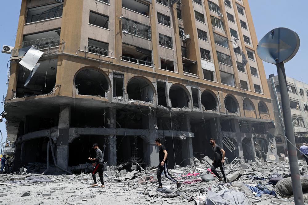 People inspect the rubble of a damaged building which was hit by an Israeli airstrike, in Gaza City, Wednesday, May 12, 2021.