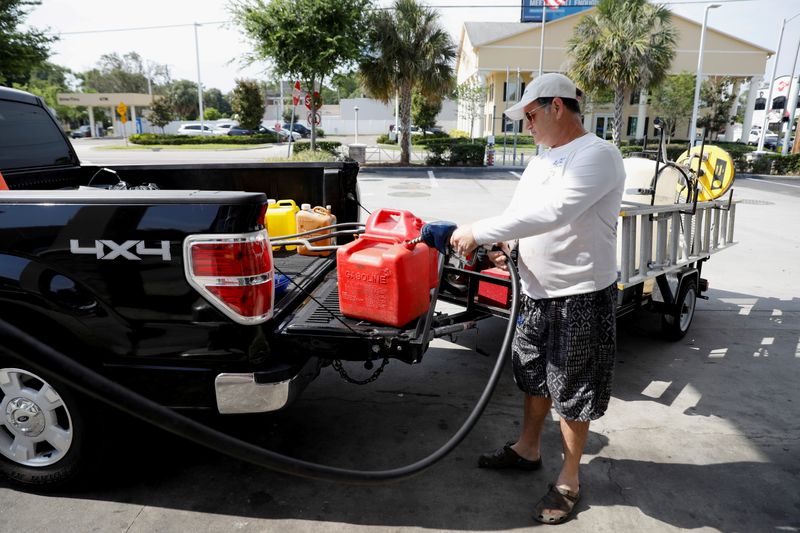 FILE PHOTO: Dax Valenti fills up gas tanks at a gas station after a cyberattack crippled the biggest fuel pipeline in the country, run by Colonial Pipeline, in Tampa, Florida, U.S., May 12, 2021. REUTERS/Octavio Jones/File Photo