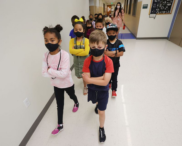 First graders Allison Mejia Medina, left, Tatum Ashy,
right and their classmates wear masks as they go to lunch at
Woodrow Wilson Elementary School in Salt Lake City on Wednesday,
May 12, 2021.