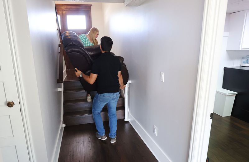 Matthew and Bethany Clewett move a chair at their new
home in Kaysville on Tuesday, May 4, 2021. They were finally able
to buy a home after 10 offers on other homes failed.