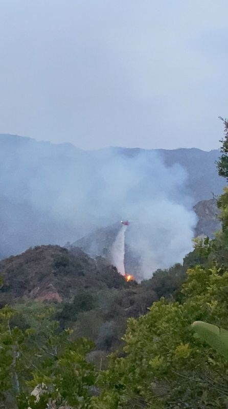 A helicopter tries to put out a brush fire in Pacific Palisades, California, U.S. May 16, 2021, in this still image obtained from social media. Mandatory credit MEGAN HERZLINGER/via REUTERS