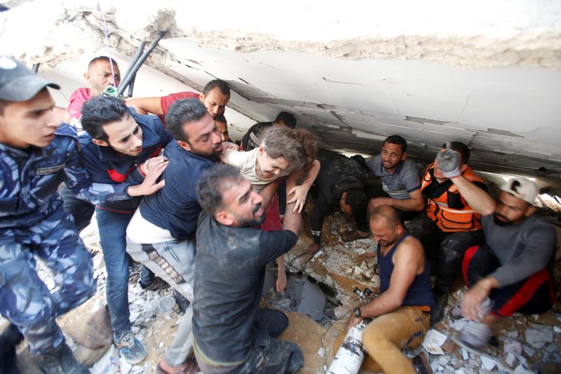 Rescuers carry Suzy Eshkuntana, 6, as they pull her from the rubble of a building at the site of Israeli air strikes, in Gaza City May 16, 2021. REUTERS/Mohammed Salem