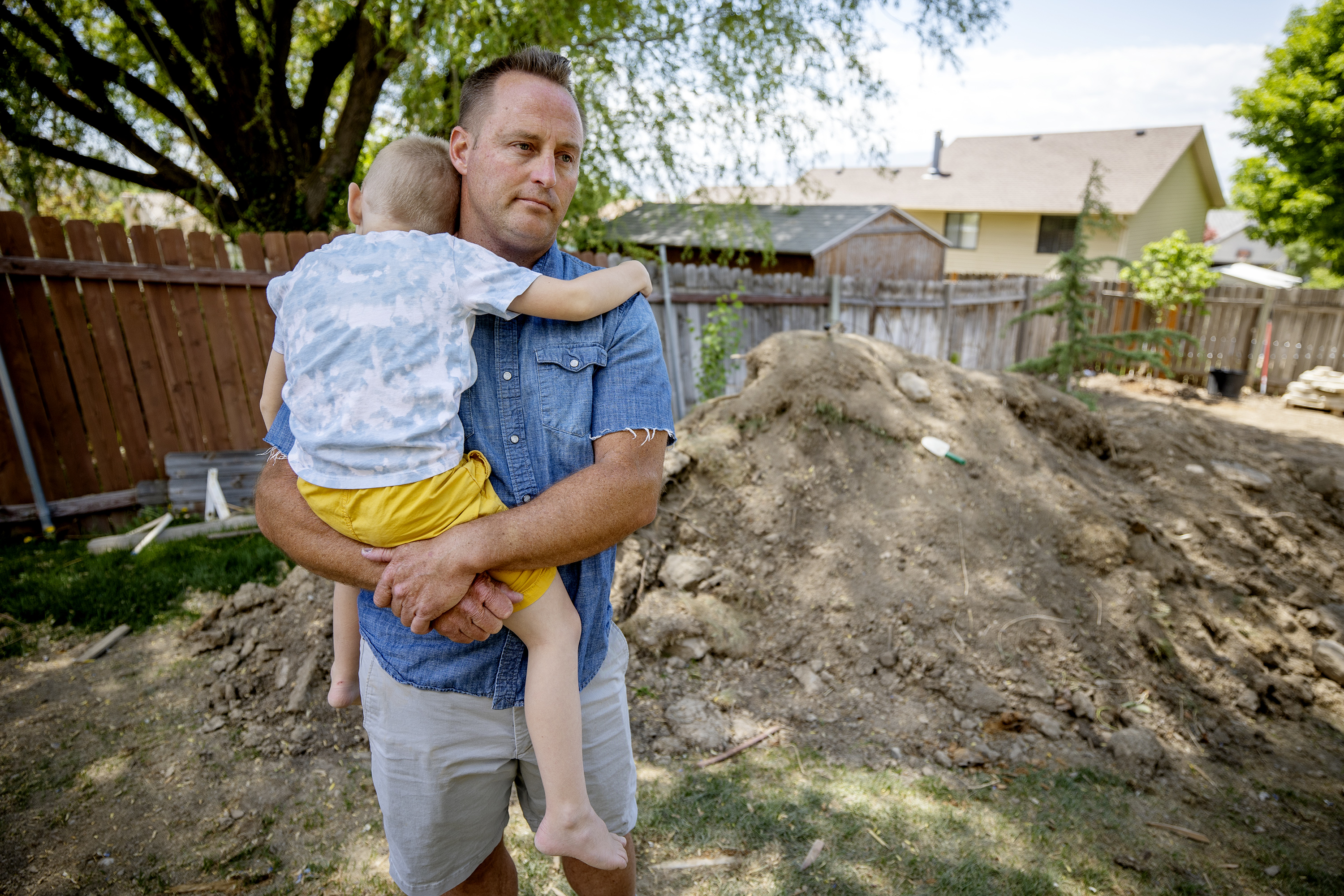 Cody Jolley, who purchased a skid steer and later found it had been stolen, holds his youngest son, CJ, at their home in Pleasant Grove on Tuesday, May 18, 2021.