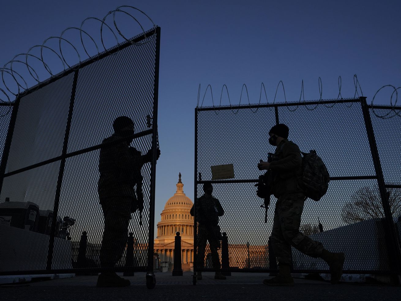 Members of the National Guard open a gate in the razor
wire topped perimeter fence around the Capitol at sunrise in
Washington on March 8. The House passed a bill to create a
bipartisan commission to investigate the Jan. 6 attack on the
Capitol by supporters of former President Donald Trump.