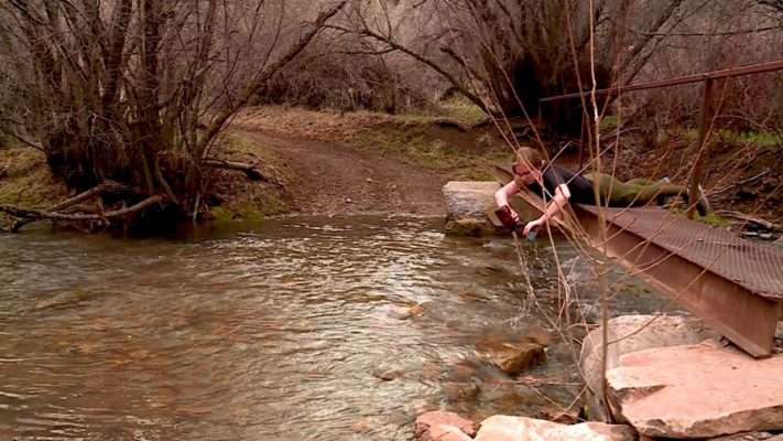 Macy Gustavus gathers a water sample in the Blacksmith Fork River.