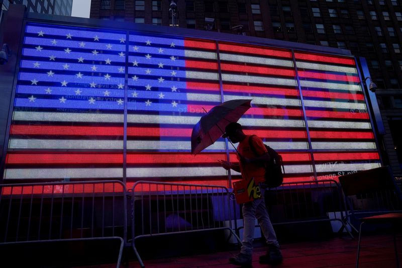 FILE PHOTO: A man with an umbrella walks through Times Square as the city feels the effects of Tropical Storm Isaias in the Manhattan borough of New York City, New York, U.S., August 4, 2020. REUTERS/Carlo Allegri/File Photo