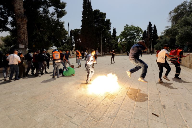 Palestinians react as Israeli security forces throw stun grenade during clashes at the compound that houses Al-Aqsa Mosque, known to Muslims as Noble Sanctuary and to Jews as Temple Mount, in Jerusalem's Old City May 21, 2021. REUTERS/Ammar Awad