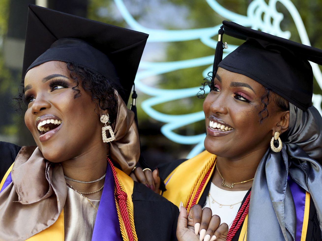 Sisters Asma Dahir, left, and Anisa Dahir take photos
before their graduation ceremony at Westminster College in Salt
Lake City on Friday, May 7, 2021.