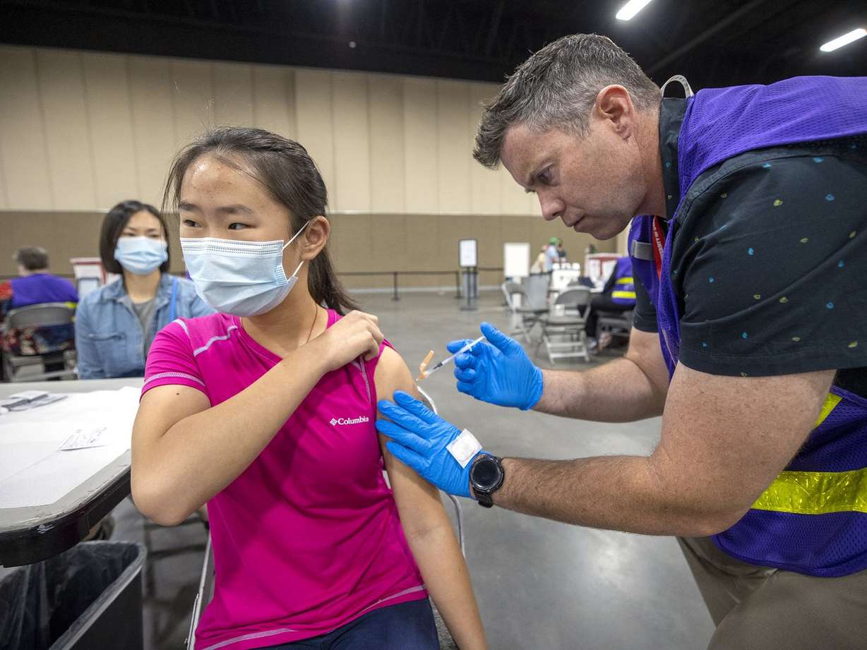 Siqi Pang, 12, looks away as Sean Murphy gives her a COVID-19 vaccination at the Mountain America Exposition Center in Sandy on Tuesday, May 18, 2021. Min Hu ,