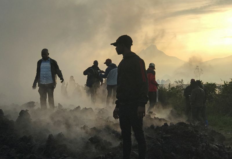 Residents walk near destroyed homes with the smouldering lava deposited by the eruption of Mount Nyiragongo volcano near Goma, in the Democratic Republic of Congo May 23, 2021.