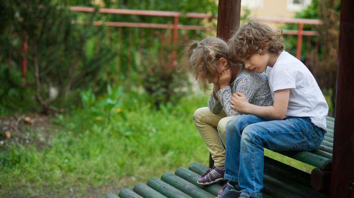 Little girl crying on the playground, and it is comforting boy. Stress, sadness, depression, problems, punishment.