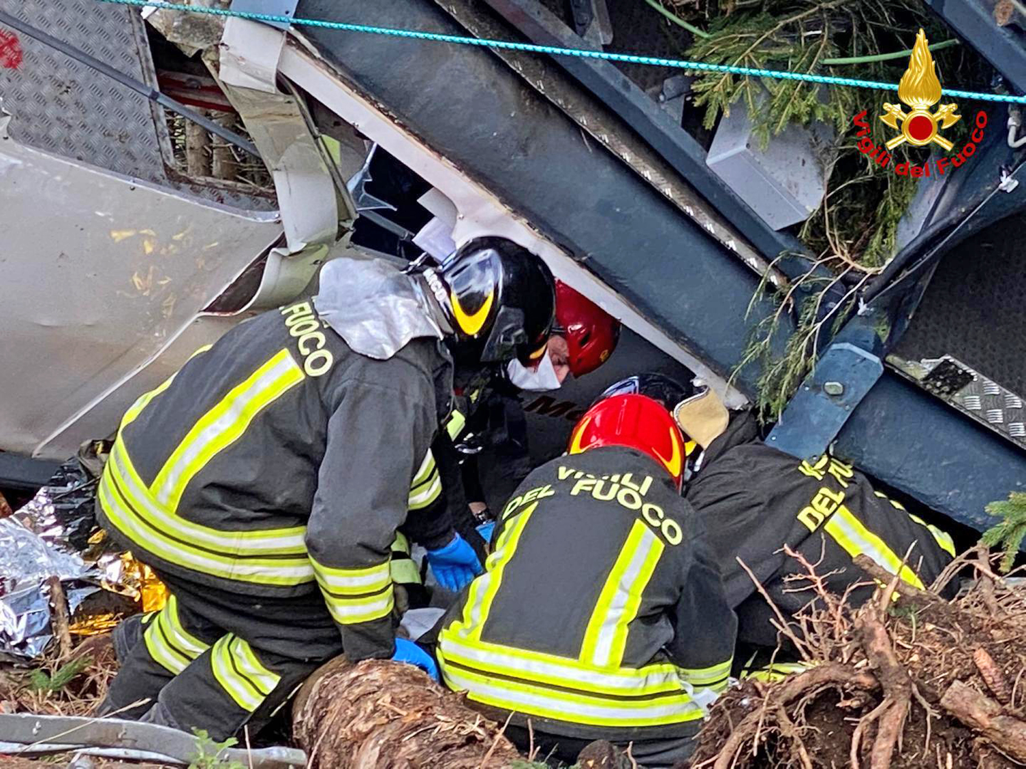 Rescuers work by the wreckage of a cable car after it collapsed near the summit of the Stresa-Mottarone line in the Piedmont region, northern Italy, Sunday, May 23, 2021. A cable car taking visitors to a mountaintop view of some of northern Italy's most picturesque lakes plummeted to the ground Sunday and then tumbled down the slope, killing at least 13 people and sending two children to the hospital, authorities said. (Italian Vigili del Fuoco Firefighters via AP) [May-24-2021]