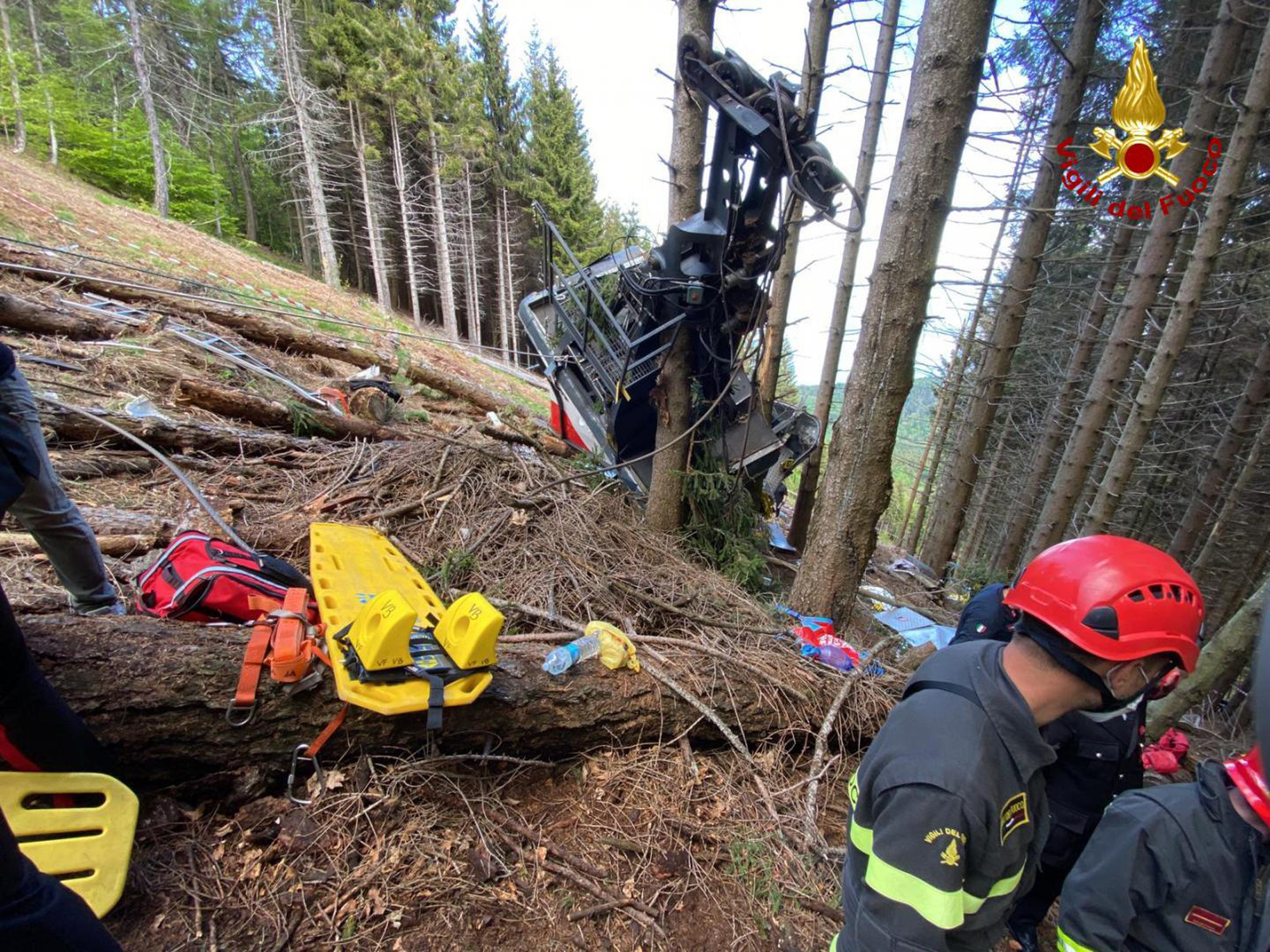 Rescuers work by the wreckage of a cable car after it collapsed near the summit of the Stresa-Mottarone line in the Piedmont region, northern Italy, Sunday, May 23, 2021. A cable car taking visitors to a mountaintop view of some of northern Italy's most picturesque lakes plummeted to the ground Sunday and then tumbled down the slope, killing at least 13 people and sending two children to the hospital, authorities said. (Italian Vigili del Fuoco Firefighters via AP) [May-24-2021]