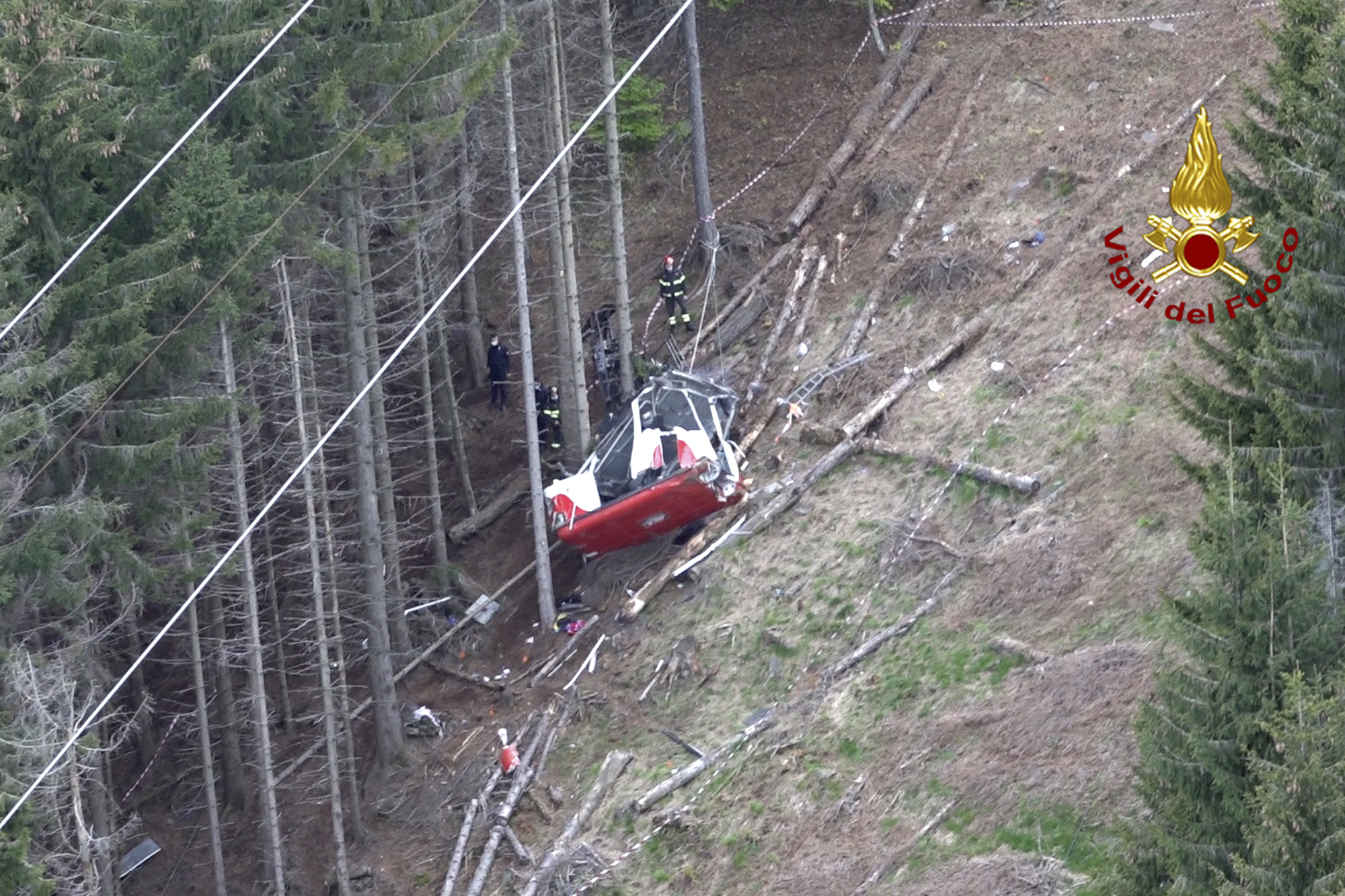 Rescuers work by the wreckage of a cable car after it collapsed near the summit of the Stresa-Mottarone line in the Piedmont region, northern Italy, as seen from the aerial photograph, Sunday, May 23, 2021. Italy’s transport minister was heading Monday, May 24, 2021 to the scene of a cable car disaster that killed 14 people when the lead cable apparently snapped and the cabin careened back down the mountain until it pulled off the line and crashed to the ground. (Vigili del Fuoco Firefighters via AP) [May-24-2021]