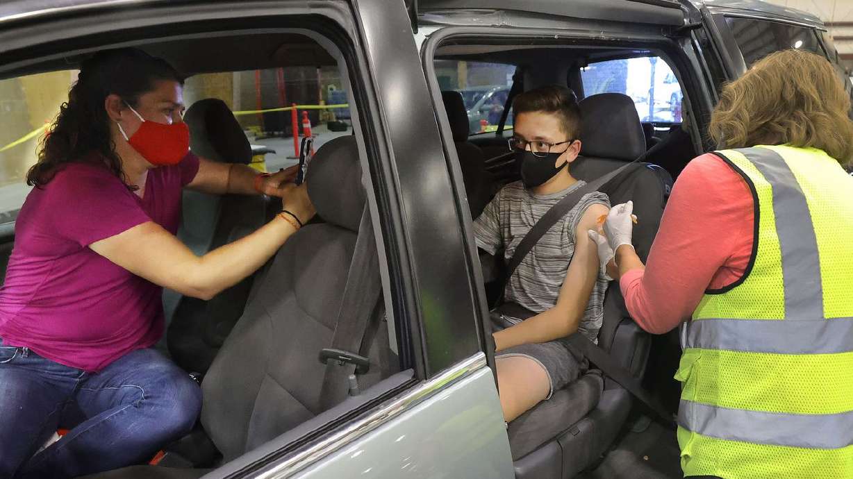 Josh Hecht, 14, center, gets a COVID-19 vaccine as his
mother Christy, left, watches at the Legacy Events Center in
Farmington on Thursday, May 13, 2021. While recent reports that
inflammation of the heart muscle may be a side effect of the
COVID-19 vaccine in some adolescents and young adults around the
country are being reviewed by the Centers for Disease Control and
Prevention, it’s business as usual for Utah’s vaccination program.