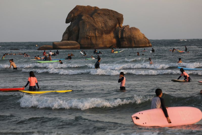 FILE PHOTO: Surfers are seen in the sea in Sanya, Hainan province, China November 26, 2020. Picture taken November 26, 2020. REUTERS/Tingshu Wang