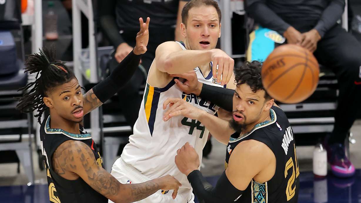 Utah Jazz forward Bojan Bogdanovic (44) passes over Memphis Grizzlies defenders Ja Morant (12) and Dillon Brooks (24) as the teams play Game 1 of their NBA playoff series at Vivint Arena in Salt Lake City on Sunday, May 23, 2021.