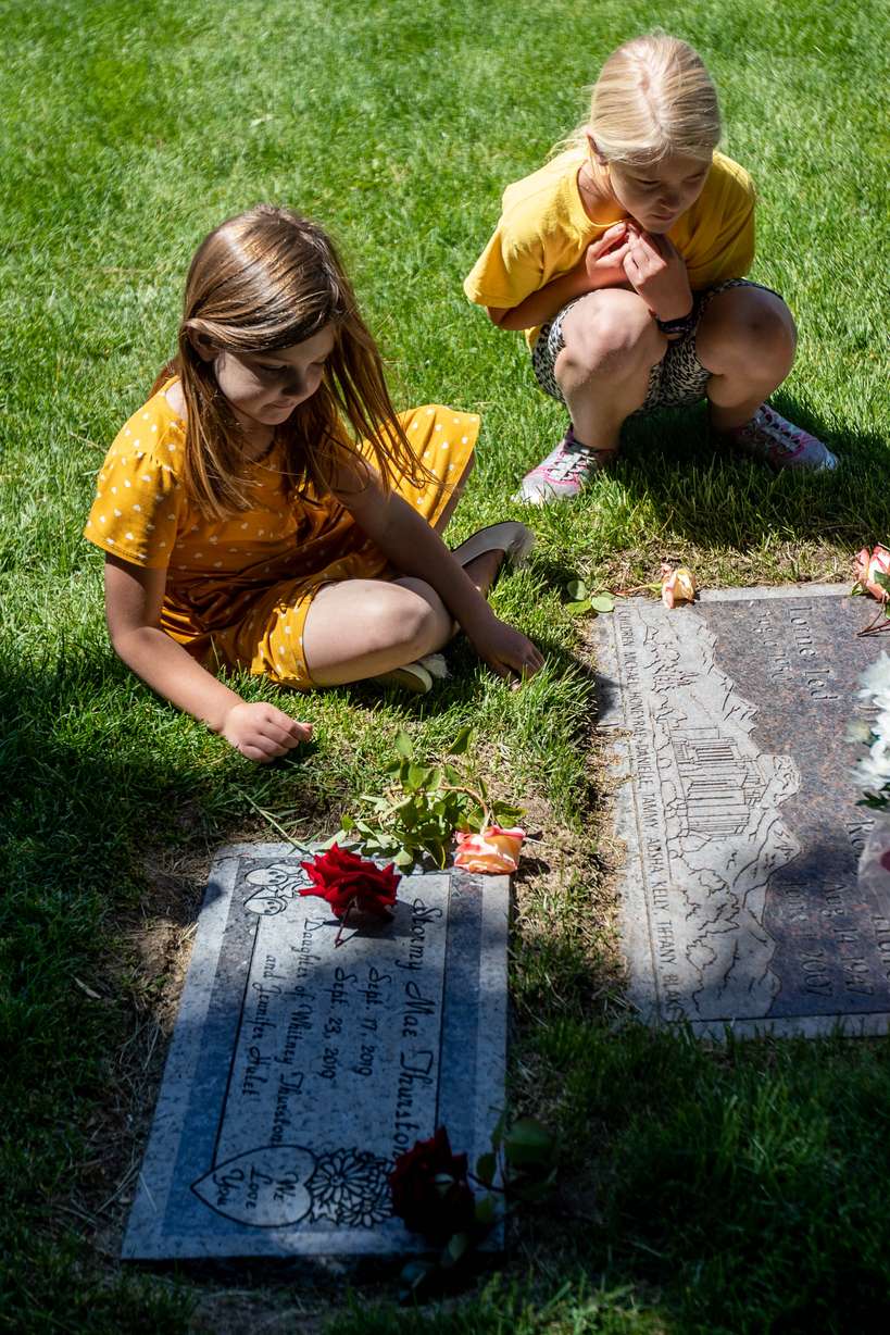 Cora Farnes, left, and her sister Jillian, right, visit a grave at Larkin Sunset Gardens Cemetery in Sandy on Monday, May 31, 2021.