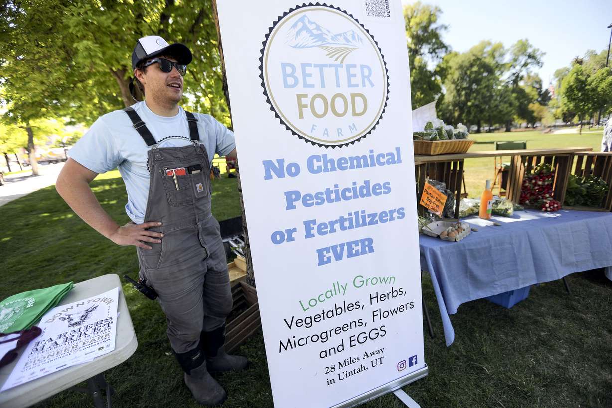Ryan Ingham, Better Food Farm chief soil officer, holds up a sign for his booth during the kickoff press conference for the Downtown Farmers Market at Pioneer Park in Salt Lake City on Wednesday, June 2, 2021.The market's 30th season starts Saturday, June 5, at the park.