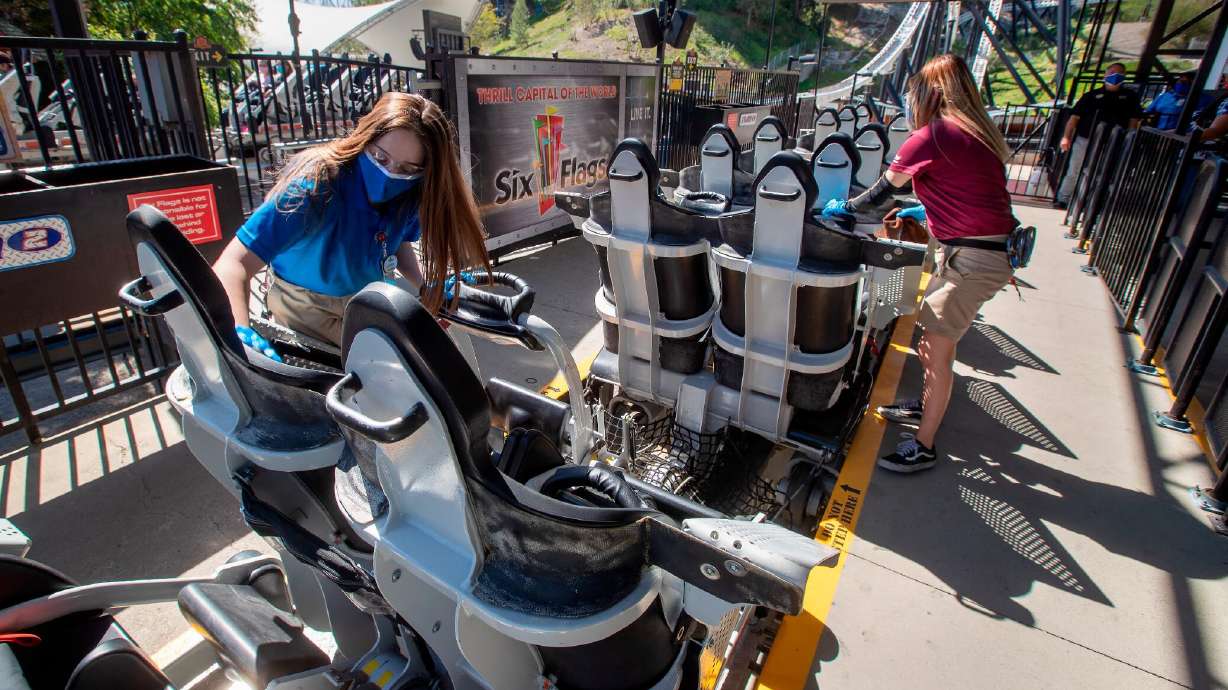 Employees sanitize roller coaster seats at Six Flags Magic Mountain in Valencia, California, on April 2 -- the second day that the park reopened after more than a year of being closed because of the pandemic.