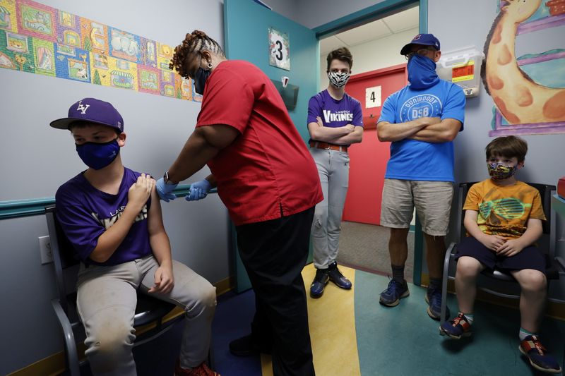 FILE: Family members look on as Jack Frilingos, 12, is inoculated with Pfizer's vaccine against coronavirus disease (COVID-19) after Georgia authorized the vaccine for ages over 12 years, at Dekalb Pediatric Center in Decatur, Georgia, U.S. May 11, 2021. REUTERS/Chris Aluka Berry/File Photo