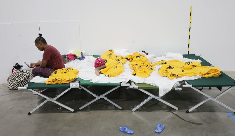 Refugee France Naolege, from Brazil, sits on her bunk as her children sleep at the Family Transfer Center in Houston on Monday, June 7, 2021.