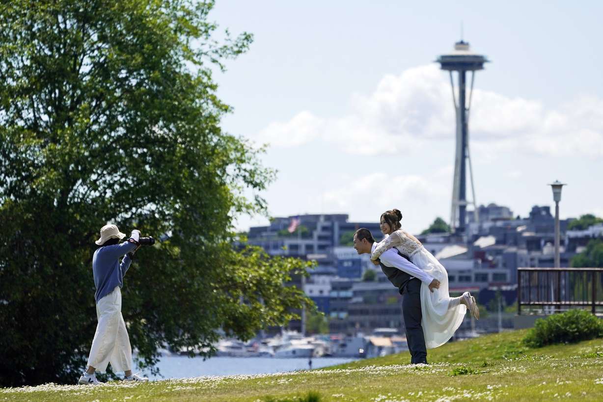 FILE- In this May 10, 2021 file photo, Tom Li, second from right, and his fiancé, Leah Li, right, pose for photos taken by Ella Chang, left, at Gas Works Park in Seattle. The couple, who live in Seattle, are originally from China and have a wedding planned later in the year for September.