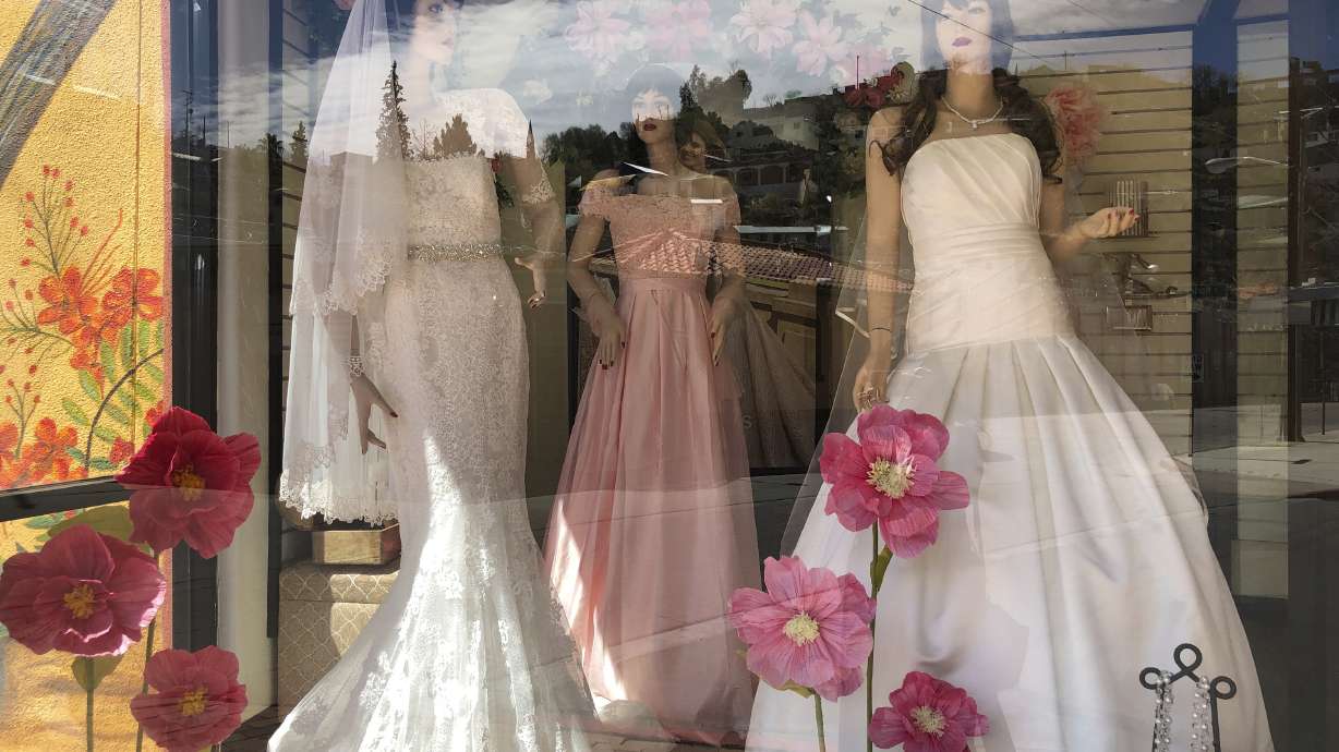 Mannequins in wedding gowns are seen in a window display on March 15, 2021, at a bridal store in Nogales, Ariz., that has been closed for nearly a year because of the pandemic. Couples in the U.S. are racing to the altar amid a vaccination-era wedding boom that has venues and other vendors in high demand.