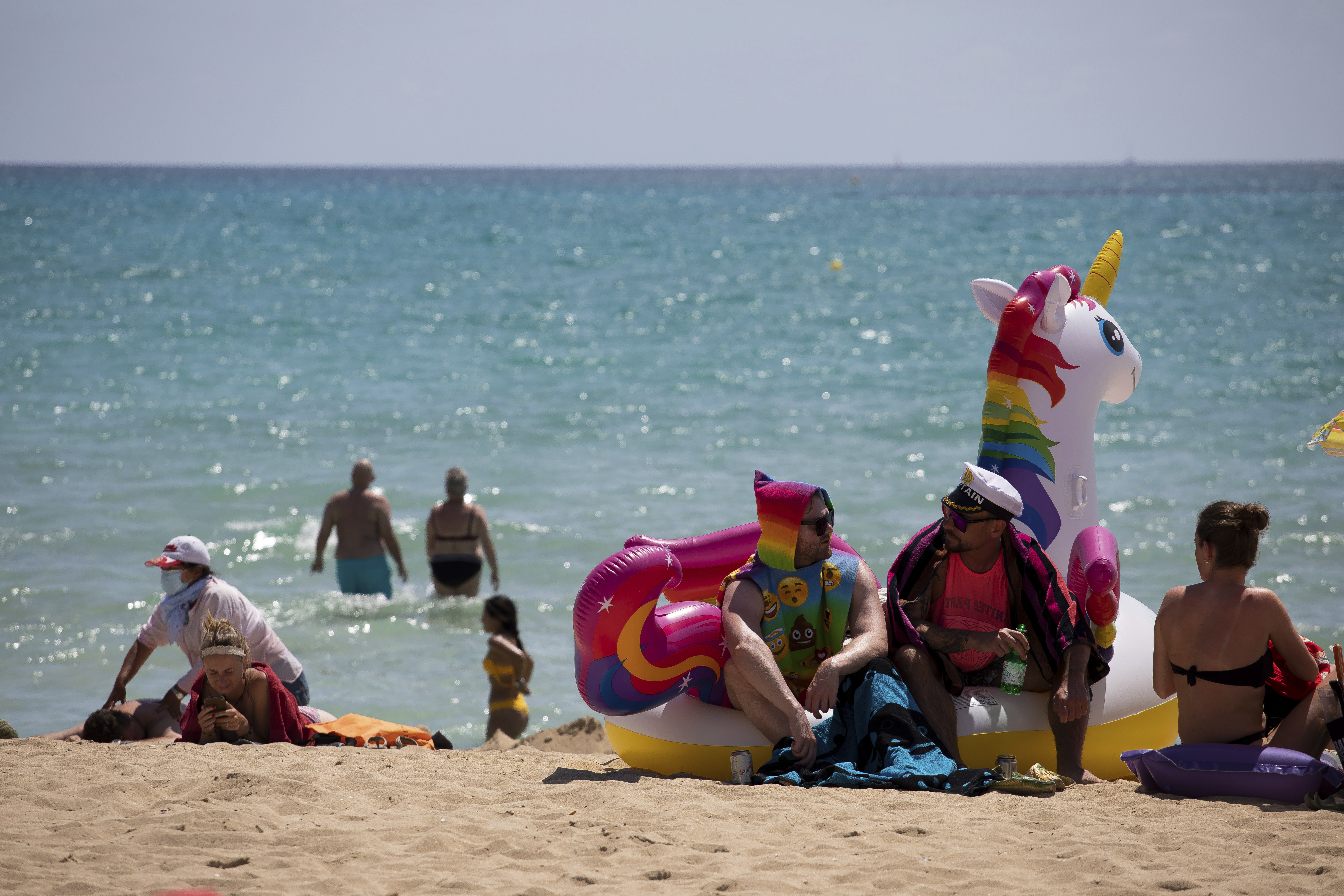 In this Monday, June 7, 2021, photo, tourists sunbathe on the beach at the Spanish Balearic Island of Mallorca, Spain.