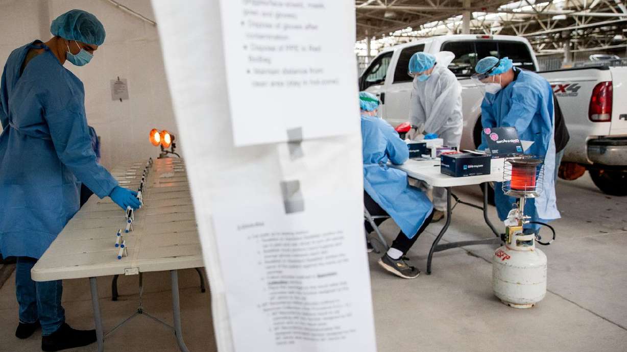 Utah National Guard Pfc. Noah Filoso, left, keeps track
of timers on COVID-19 rapid tests at the Fairpark in Salt Lake City
on Saturday, Jan. 23, 2021.