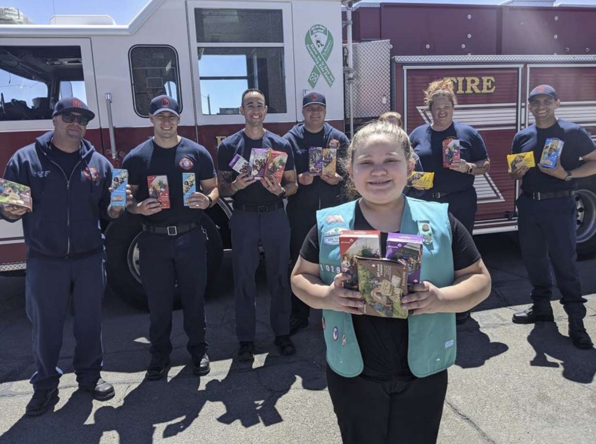 FILE: This undated photo provided by Girl Scouts of New Mexico Trails shows a scout donating cookies to firefighters in Rio Rancho, New Mexico, as part of the Hometown Heroes program. As the coronavirus pandemic wore into the spring selling season, many Girl Scout troops nixed their traditional cookie booths for safety reasons. That resulted in millions of boxes of unsold cookies. (Girl Scouts of New Mexico Trails via AP)
