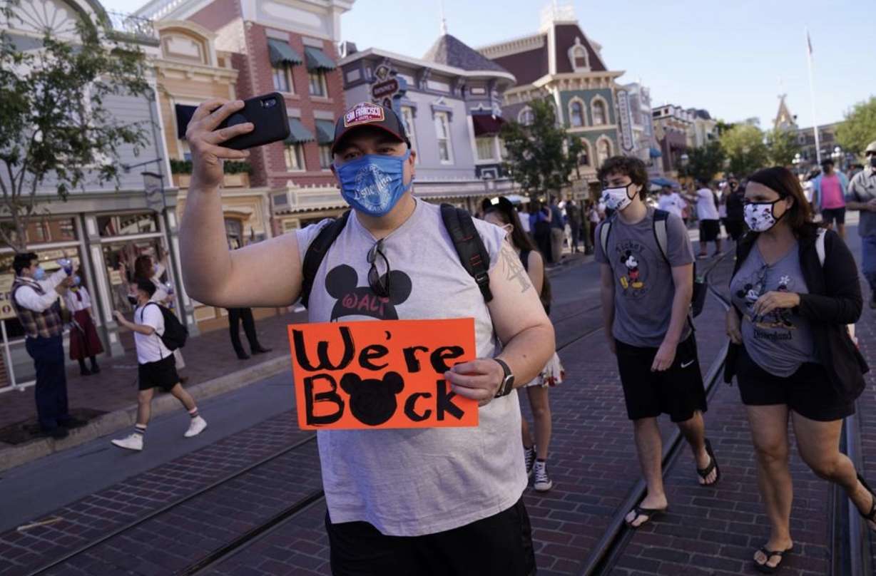 ILE - In this Friday, April 30, 2021, file photo, visitors walk down Main Street USA at Disneyland in Anaheim, Calif. California, the first state in America to put in place a coronavirus lockdown, is now turning a page on the pandemic. Most of California's coronavirus restrictions will disappear Tuesday, June 15, 2021. (AP Photo/Jae Hong, File)