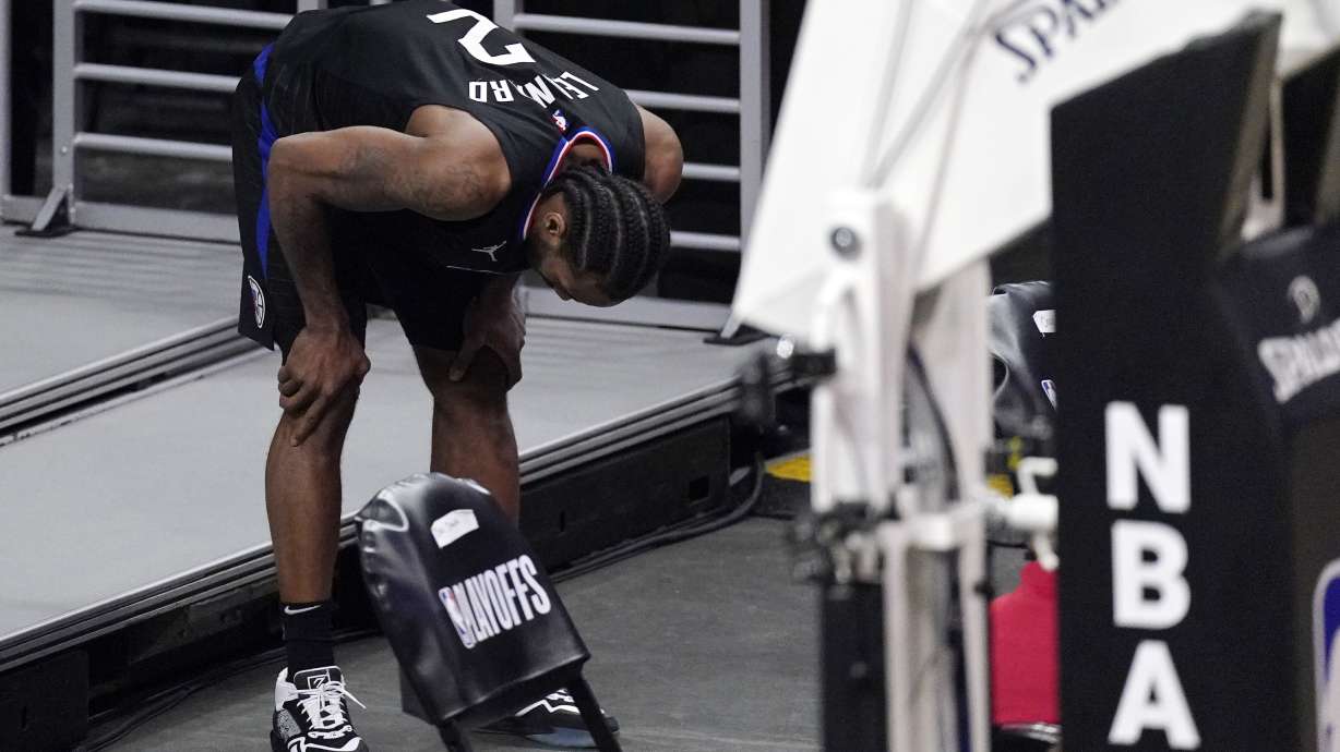 Los Angeles Clippers forward Kawhi Leonard holds his knee after stepping awkwardly during the second half in Game 4 of a second-round NBA basketball playoff series against the Utah Jazz Monday, June 14, 2021, in Los Angeles.