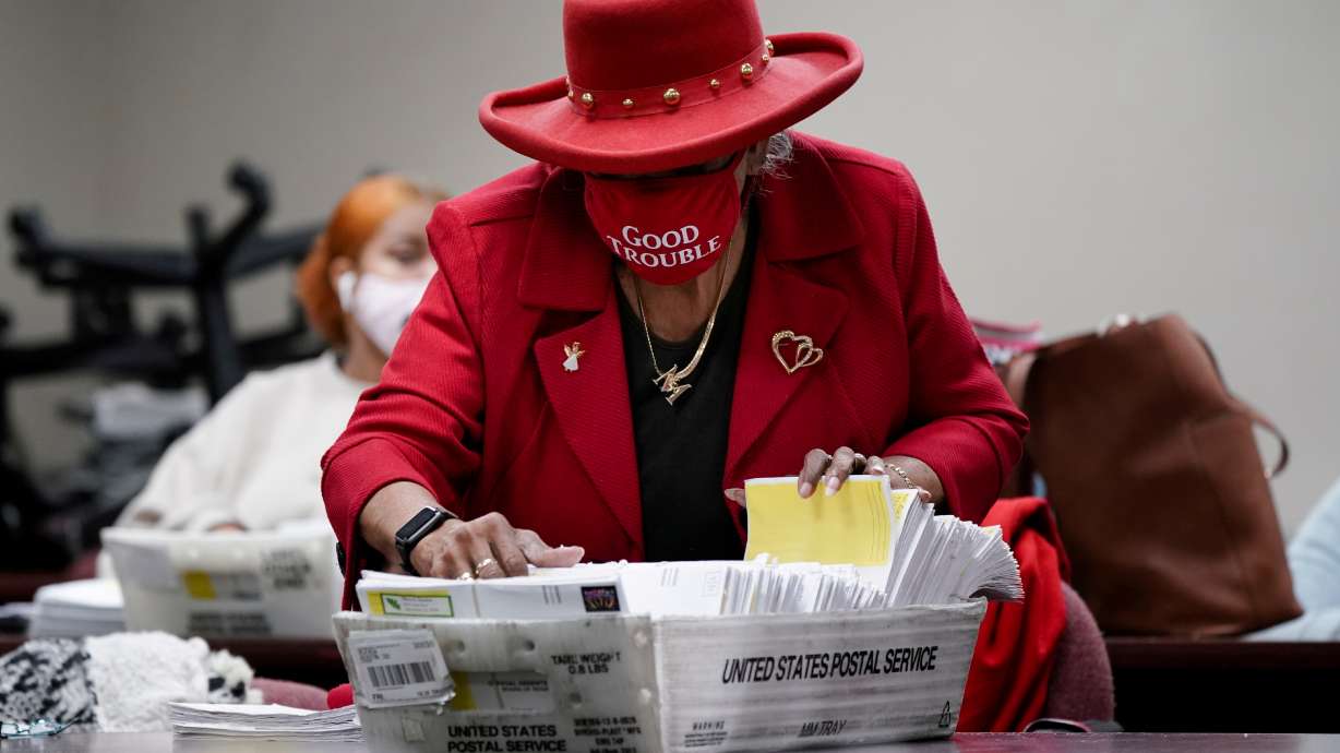 A DeKalb County election worker wearing a 'Good Trouble' face mask sorts empty absentee ballot envelopes following the Senate runoff elections in Decatur, Georgia, Jan. 6, 2021.